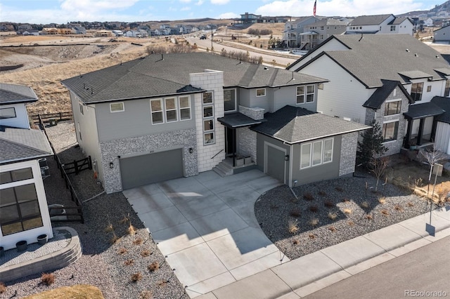 view of front of property with an attached garage, a shingled roof, concrete driveway, stone siding, and a residential view