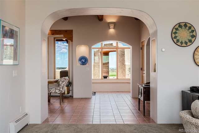 tiled foyer with a baseboard radiator, arched walkways, and plenty of natural light