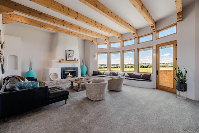 living room with healthy amount of natural light, beamed ceiling, carpet flooring, and a glass covered fireplace