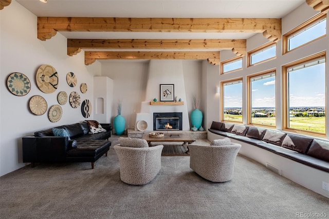carpeted living area with a glass covered fireplace and beam ceiling