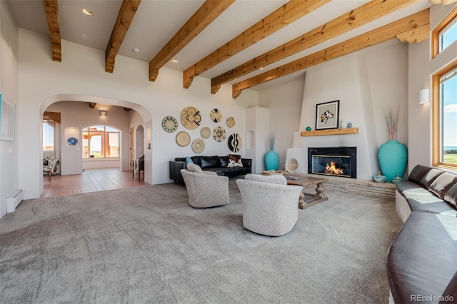 living room with arched walkways, carpet floors, a large fireplace, healthy amount of natural light, and beamed ceiling