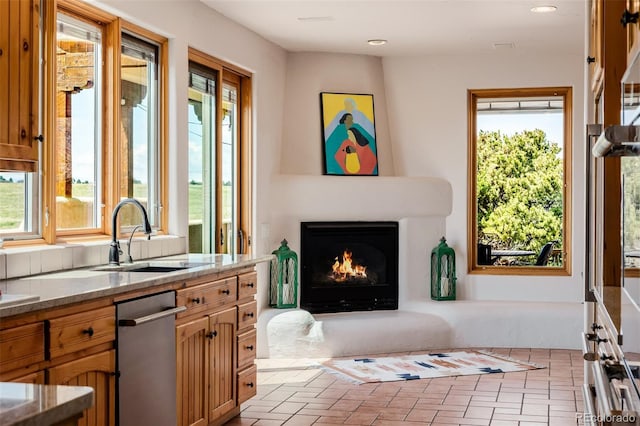 kitchen with a sink, healthy amount of natural light, a lit fireplace, dishwasher, and recessed lighting