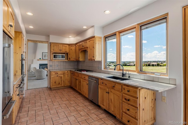 kitchen featuring stainless steel appliances, a sink, decorative backsplash, brick patterned flooring, and light stone countertops