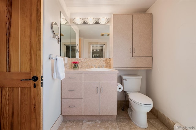 bathroom with toilet, vanity, and baseboards