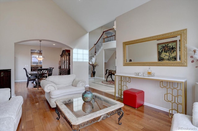 15857 E Aberdeen Ave, Centennial, CO 80016 - living area featuring arched walkways, wood-type flooring, high vaulted ceiling, baseboards, and stairs