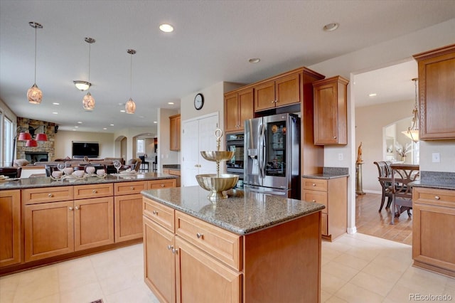 15857 E Aberdeen Ave, Centennial, CO 80016 - kitchen featuring stainless steel refrigerator with ice dispenser, a center island, open floor plan, dark stone countertops, and a stone fireplace