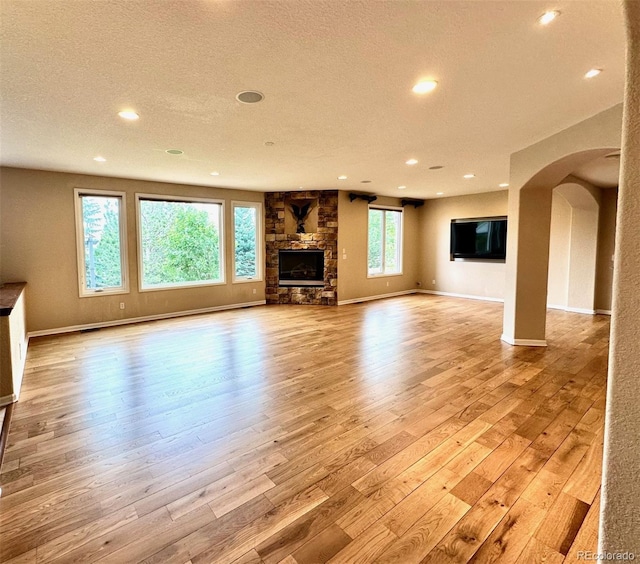 15857 E Aberdeen Ave, Centennial, CO 80016 - unfurnished living room featuring arched walkways, light wood finished floors, recessed lighting, baseboards, and a textured ceiling