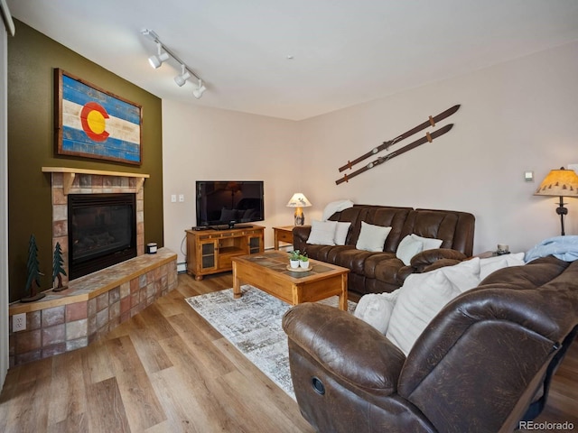 10000 Ryan Gulch Rd Unit 114, Silverthorne, CO 80498 - living area with wood finished floors, a tile fireplace, rail lighting, and baseboard heating