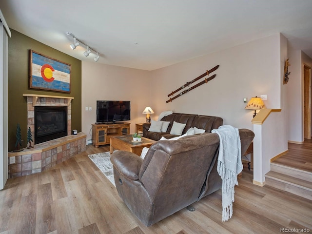10000 Ryan Gulch Rd Unit 114, Silverthorne, CO 80498 - living room with wood finished floors, a tiled fireplace, rail lighting, baseboard heating, and baseboards