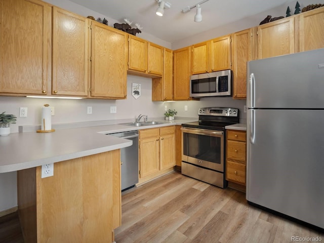 10000 Ryan Gulch Rd Unit 114, Silverthorne, CO 80498 - kitchen featuring appliances with stainless steel finishes, a sink, a peninsula, light wood finished floors, and light countertops