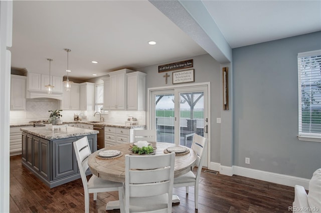 kitchen featuring stainless steel dishwasher, a sink, white cabinetry, and backsplash