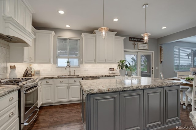 kitchen featuring a center island, a sink, stainless steel gas range, custom exhaust hood, and white cabinetry