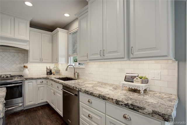 kitchen with light stone counters, a sink, white cabinetry, and stainless steel appliances