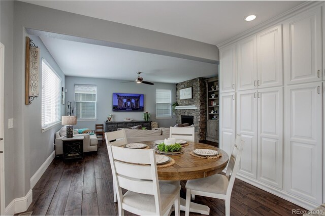 dining room featuring baseboards, a ceiling fan, dark wood-style floors, and a fireplace
