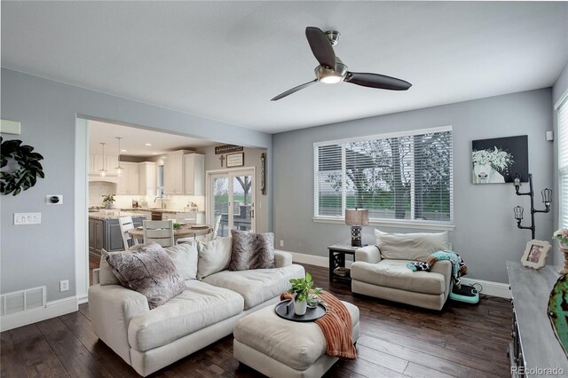living area with a ceiling fan, baseboards, visible vents, and dark wood-type flooring