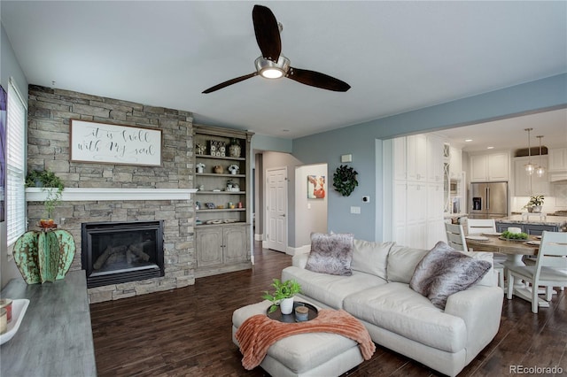 living room with a ceiling fan, dark wood finished floors, and a fireplace