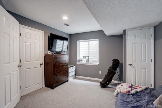 bedroom with baseboards, light carpet, and a textured ceiling