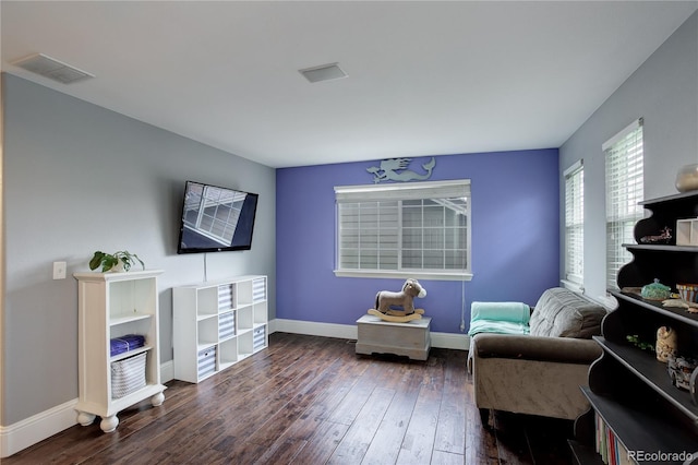 living area featuring baseboards, wood-type flooring, and visible vents