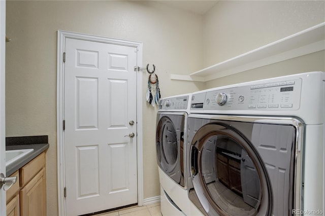 laundry area with a sink, washer and clothes dryer, cabinet space, and light tile patterned flooring