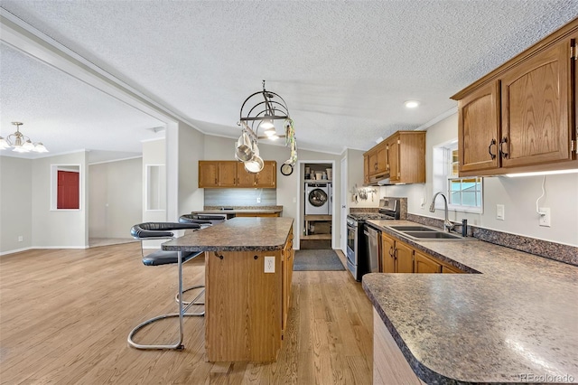5856 John Ross Ct, Peyton, CO 80831 - kitchen with stainless steel gas range, a sink, washer / dryer, a textured ceiling, and a chandelier