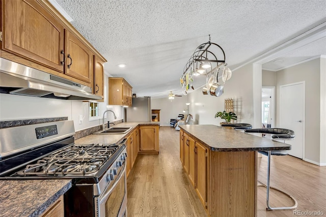 5856 John Ross Ct, Peyton, CO 80831 - kitchen featuring stainless steel gas range, a sink, under cabinet range hood, a kitchen breakfast bar, and ceiling fan