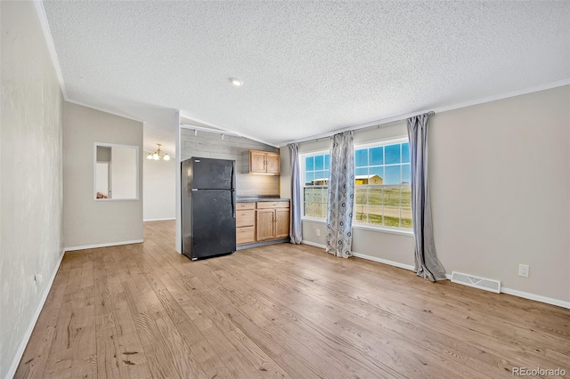 5856 John Ross Ct, Peyton, CO 80831 - unfurnished living room with a textured ceiling, light wood-type flooring, vaulted ceiling, baseboards, and a chandelier