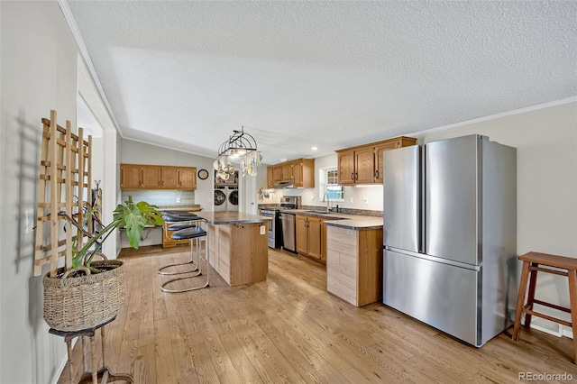 5856 John Ross Ct, Peyton, CO 80831 - kitchen with appliances with stainless steel finishes, washing machine and dryer, light wood-style flooring, a breakfast bar area, and a textured ceiling