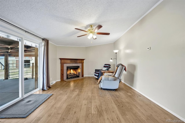 5856 John Ross Ct, Peyton, CO 80831 - unfurnished room with light wood-type flooring, a tile fireplace, a ceiling fan, crown molding, and a textured ceiling
