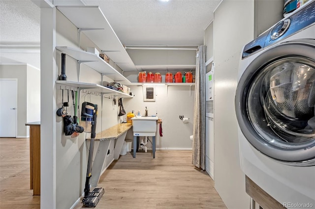5856 John Ross Ct, Peyton, CO 80831 - laundry area featuring washer / clothes dryer, light wood finished floors, and a textured ceiling