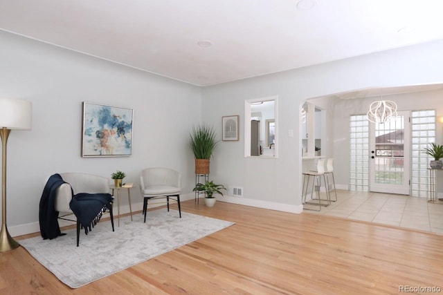 living area with light wood-type flooring and an inviting chandelier