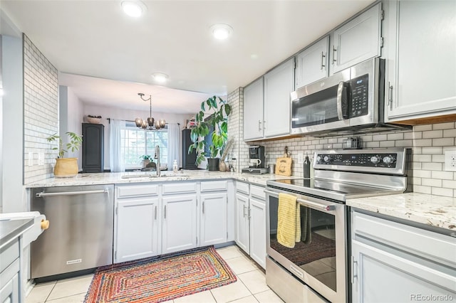 kitchen featuring appliances with stainless steel finishes, a sink, a chandelier, backsplash, and recessed lighting