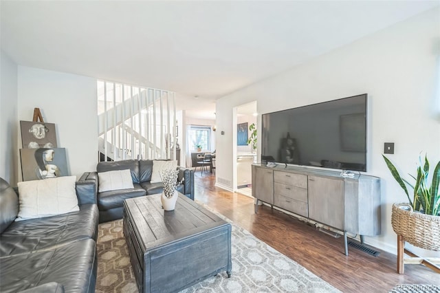 living area with wood finished floors, baseboards, and stairs