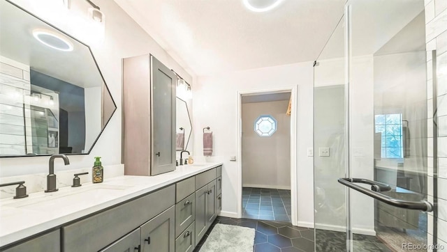 bathroom featuring double vanity, a stall shower, tile patterned flooring, and baseboards