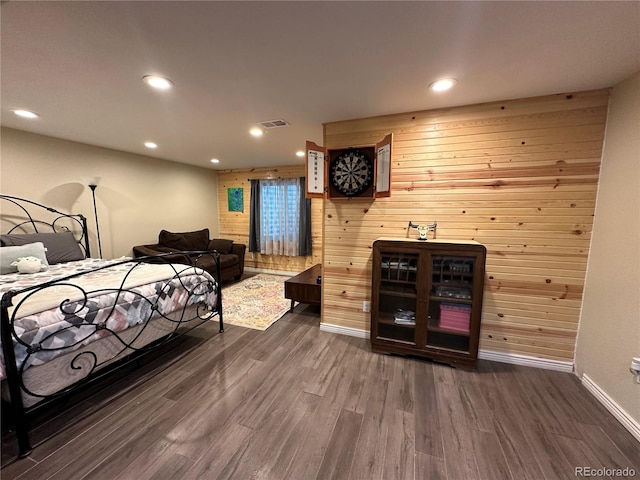 bedroom with dark hardwood / wood-style floors and wood walls