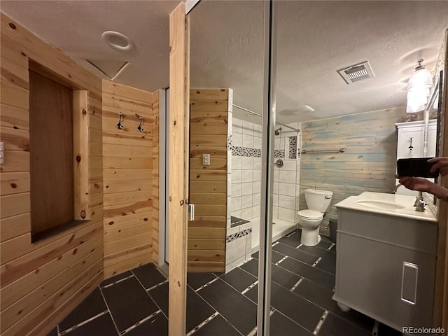 full bath with vanity, a stall shower, and wood walls