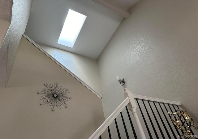 staircase with a skylight and a textured wall