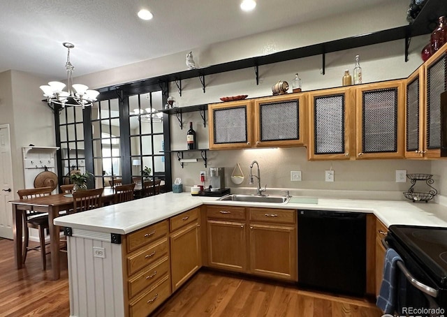 kitchen featuring sink, hanging light fixtures, kitchen peninsula, hardwood / wood-style floors, and black appliances