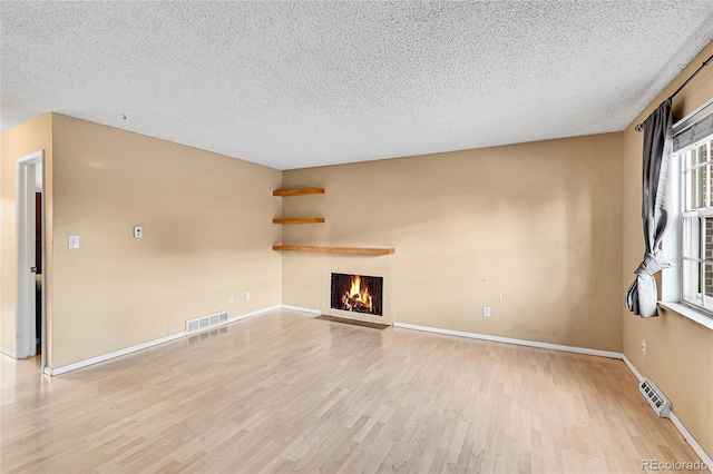 unfurnished living room featuring a textured ceiling and light hardwood / wood-style floors