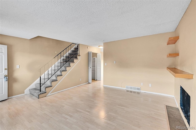 unfurnished living room with light hardwood / wood-style floors and a textured ceiling