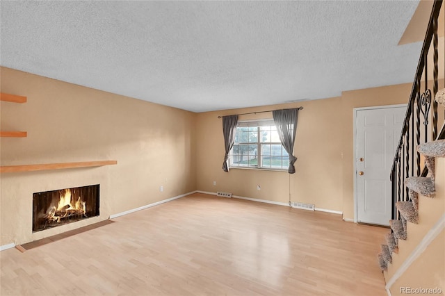 unfurnished living room with a textured ceiling and hardwood / wood-style flooring