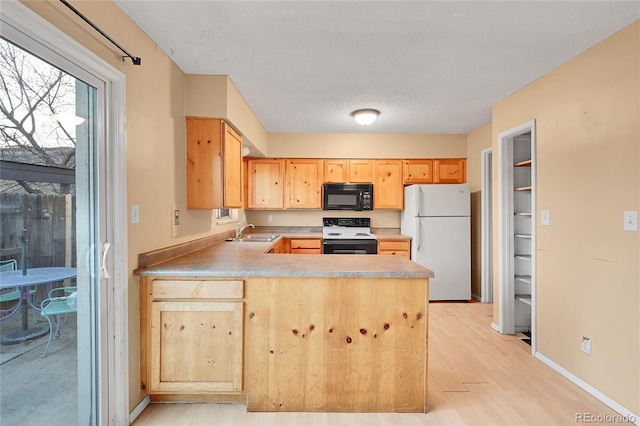 kitchen featuring white appliances, light wood-type flooring, a textured ceiling, light brown cabinetry, and kitchen peninsula