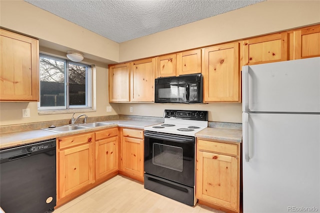 kitchen featuring light brown cabinetry, a textured ceiling, sink, black appliances, and light hardwood / wood-style flooring