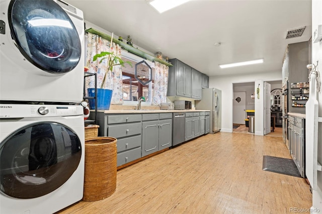 7400 W Quincy Ave, Littleton, CO 80123 - laundry area with stacked washer and clothes dryer and light wood-style flooring