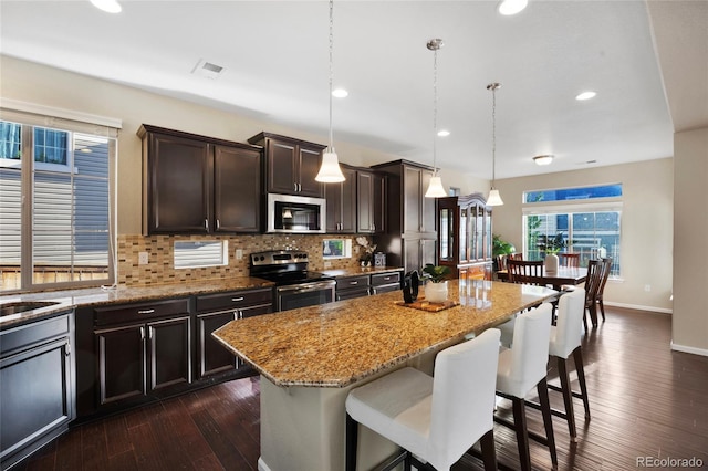 4875 S Catawba St, Aurora, CO 80016 - kitchen featuring appliances with stainless steel finishes, light stone counters, decorative backsplash, a breakfast bar, and dark wood-style flooring