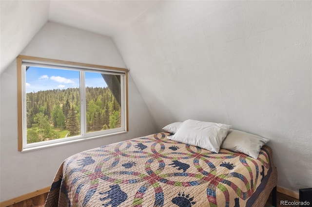 413 W Lake Dr, Divide, CO 80814 - bedroom with vaulted ceiling, a wooded view, and wood finished floors