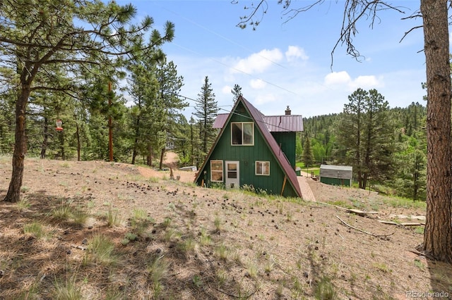 413 W Lake Dr, Divide, CO 80814 - back of house featuring a chimney, a metal roof, and a wooded view
