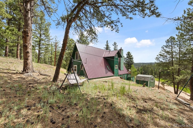 413 W Lake Dr, Divide, CO 80814 - view of property exterior featuring a chimney, a metal roof, and a storage shed