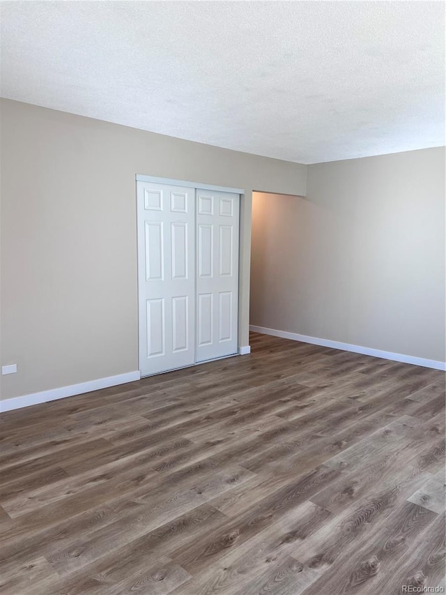 unfurnished bedroom with dark hardwood / wood-style floors, a closet, and a textured ceiling