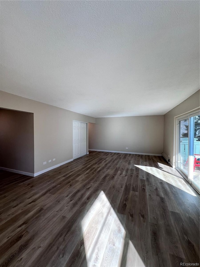 unfurnished living room with dark wood-type flooring and a textured ceiling