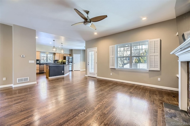 unfurnished living room featuring dark wood-type flooring and ceiling fan